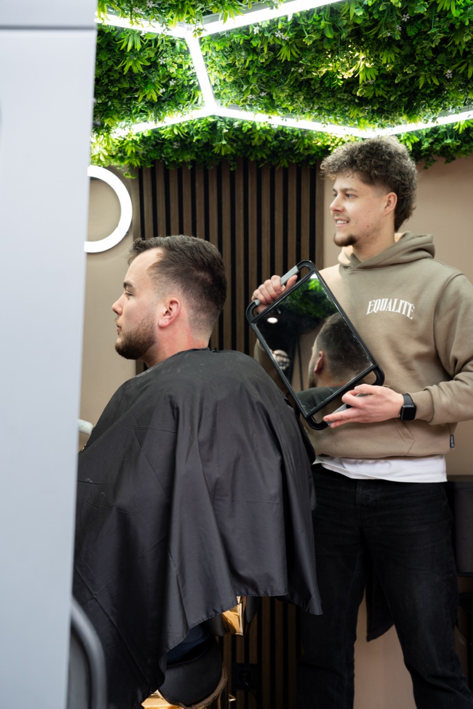 De barber laat het resultaat zien in de spiegel
