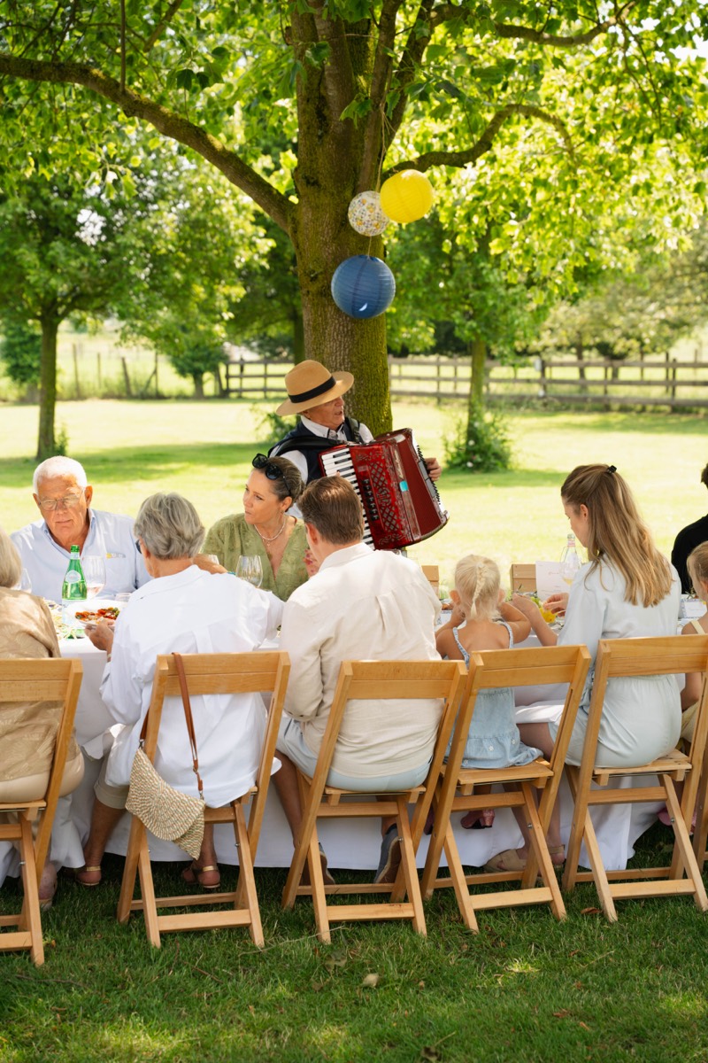 Gasten aan tafel met accordeonist