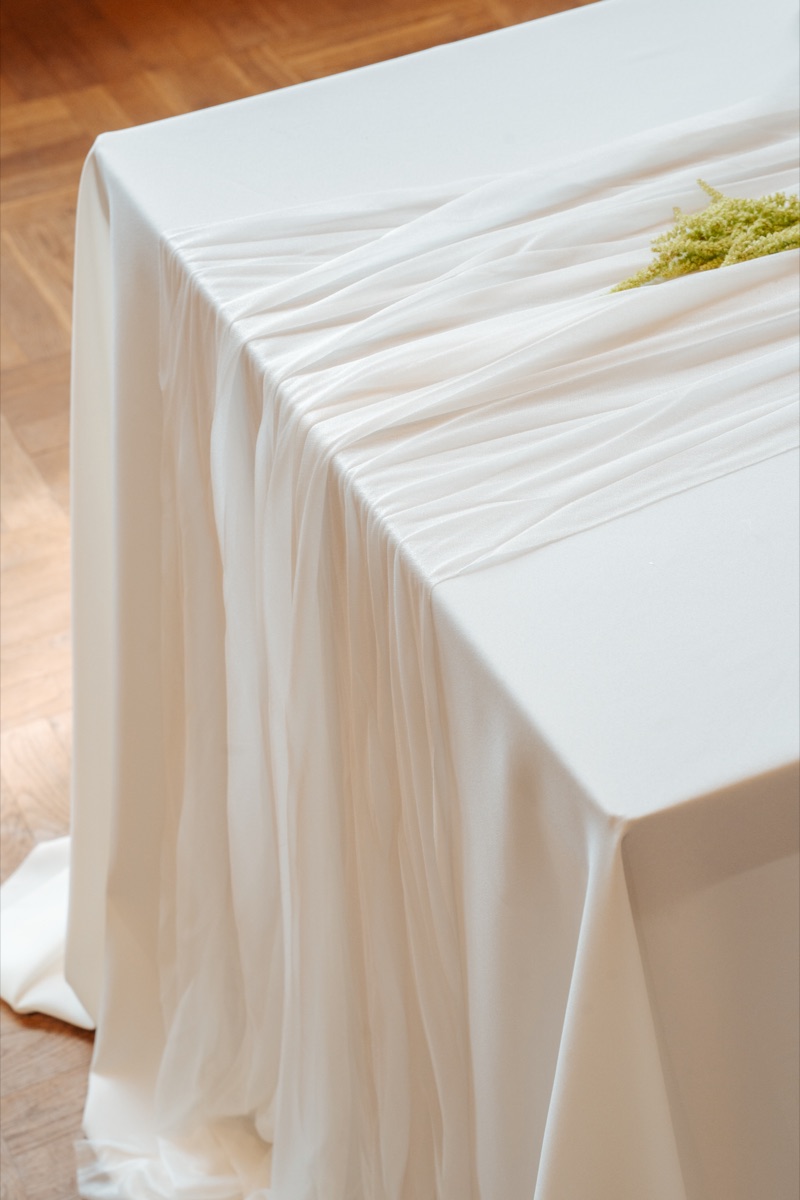 Een tafel aangekleed met wit doek en een takje groen